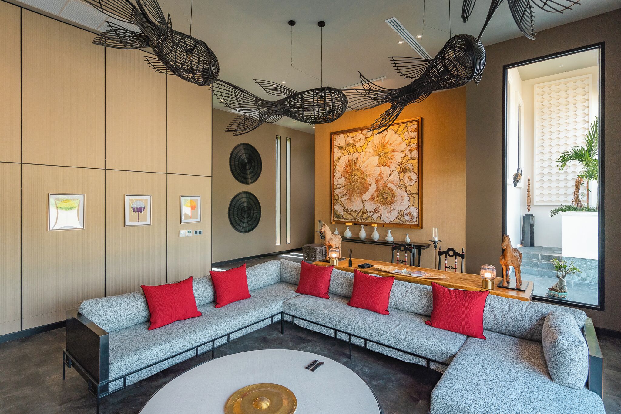 Un salon moderne avec un canapé d’angle, une table basse ronde et un grand tableau abstrait accroché au mur.