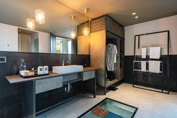 Un baño moderno con un espejo grande, dos lavamanos y una cabina de ducha de vidrio.