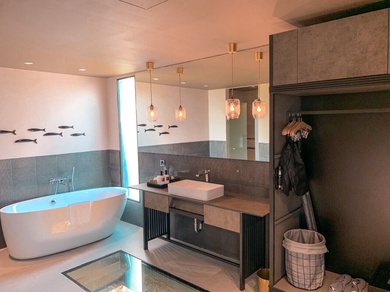 A modern bathroom with a freestanding bathtub, a vanity with a sink, and a large mirror.
