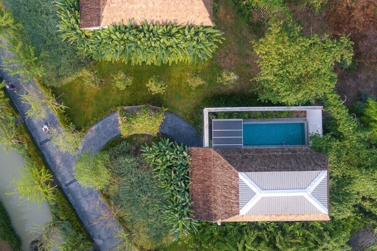 Eine Vogelperspektive auf ein modernes Haus mit Schwimmbad, umgeben von üppigem Grün und einem kleinen Garten.