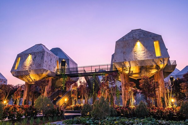 A futuristic building with two large, hexagonal structures connected by a bridge. - Thann Wellness Destination (Bang Sai)