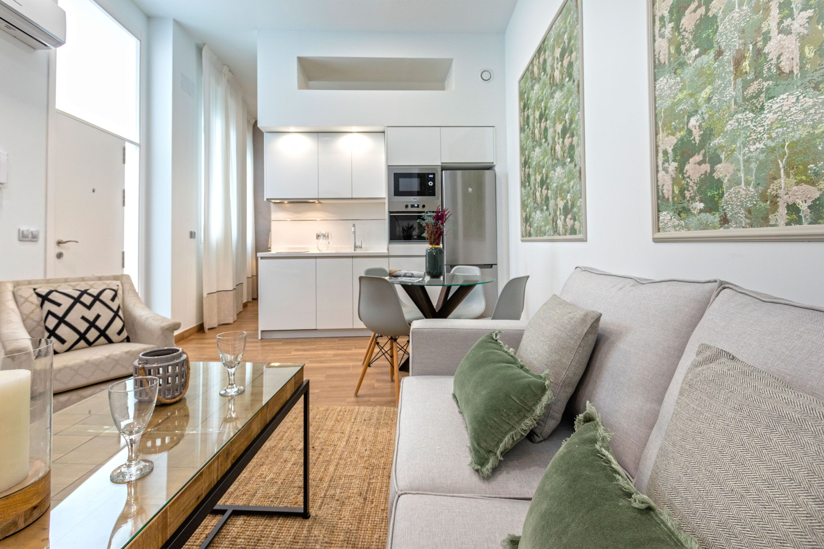Una sala de estar moderna con un sofá, una mesa de centro y un comedor con sillas y una mesa de vidrio.