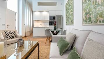Una sala de estar moderna con un sofá, una mesa de centro y un comedor con sillas y una mesa de vidrio.