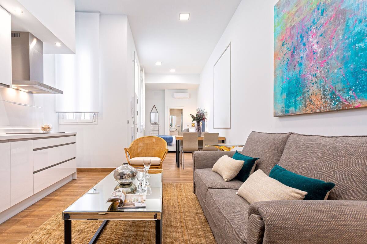Un salon moderne avec un canapé, une table basse et un coin repas à l’arrière-plan.