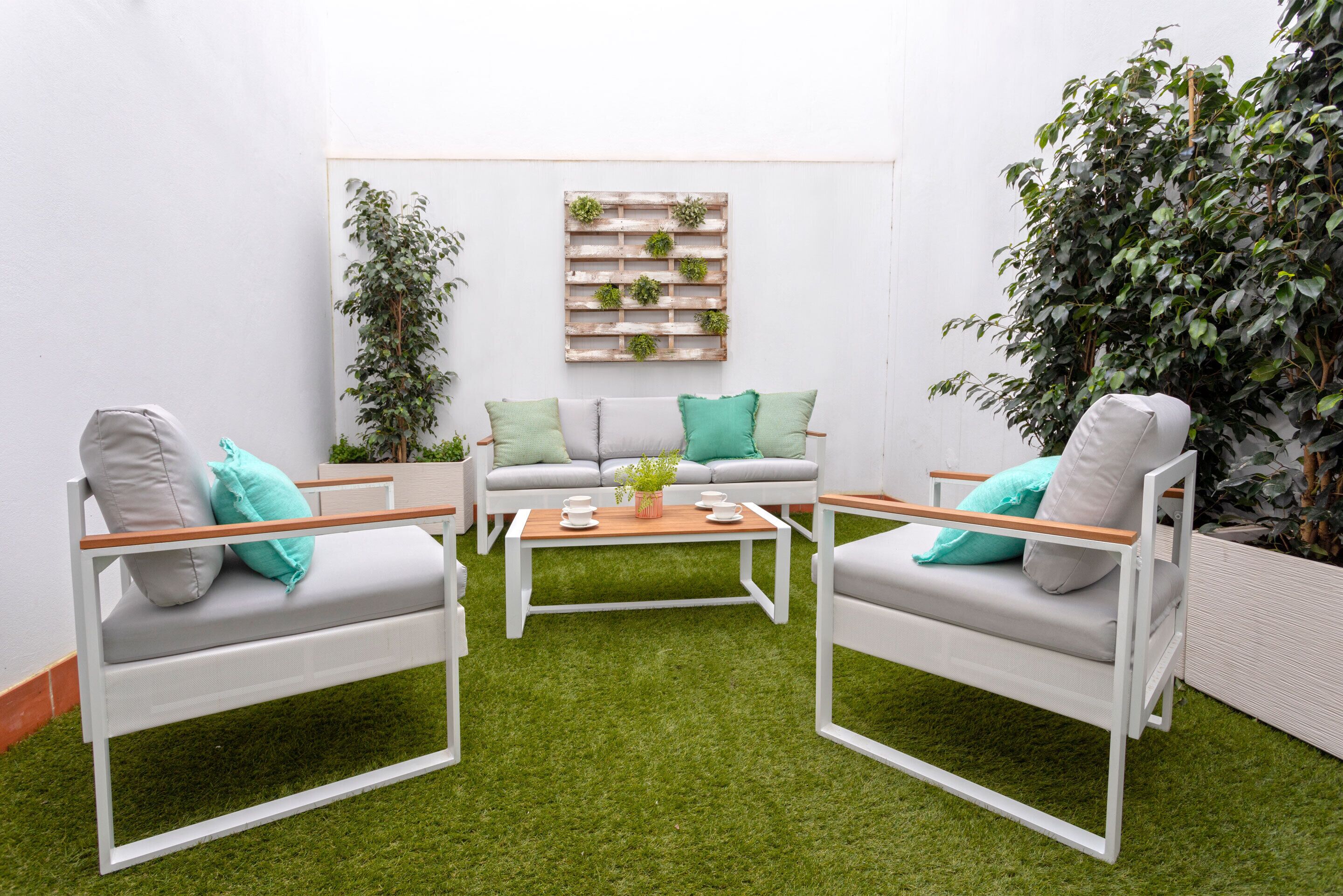 A modern outdoor seating area with two white chairs, a white sofa, and a coffee table.