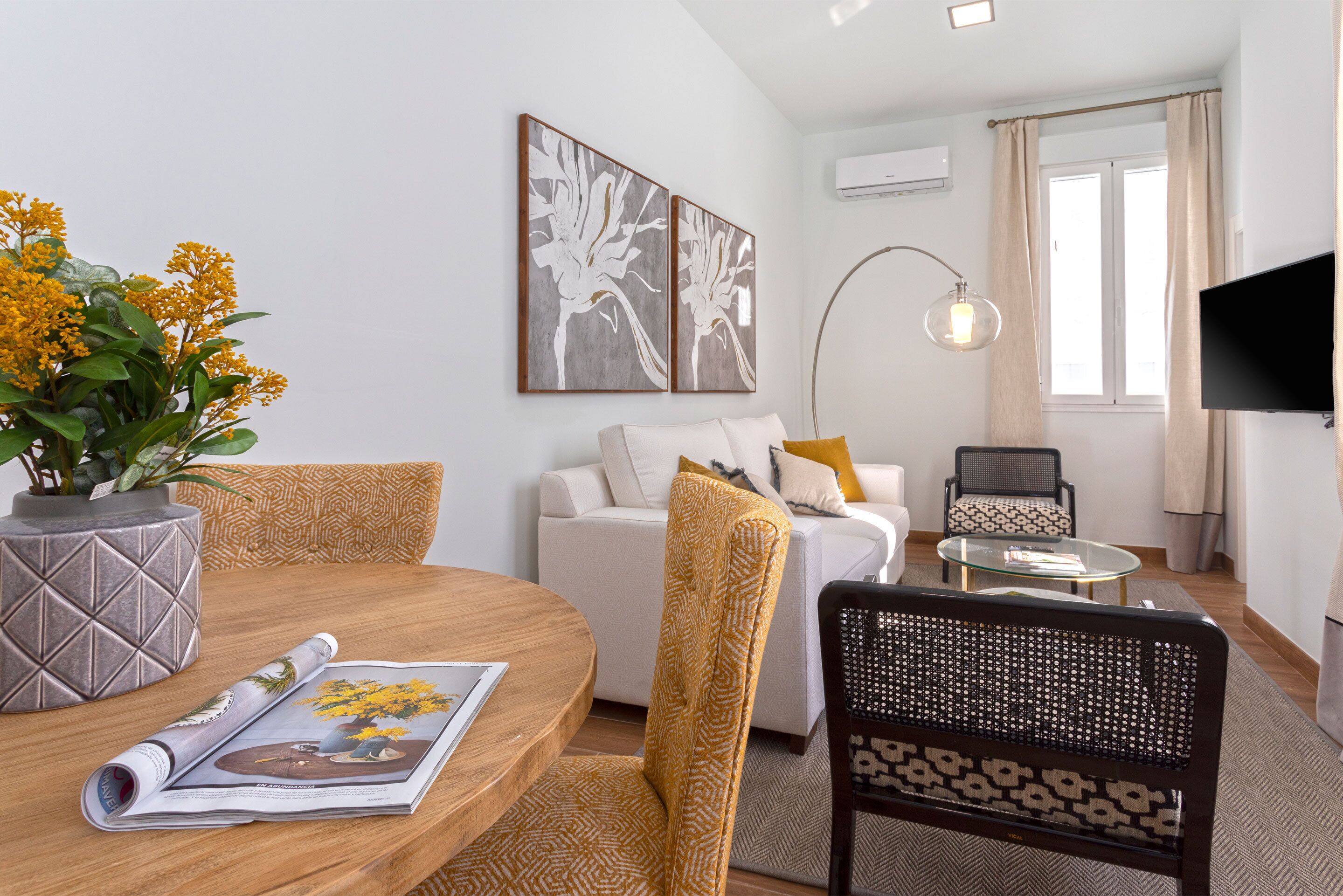 A modern living room with a round wooden table, a sofa, and a TV.