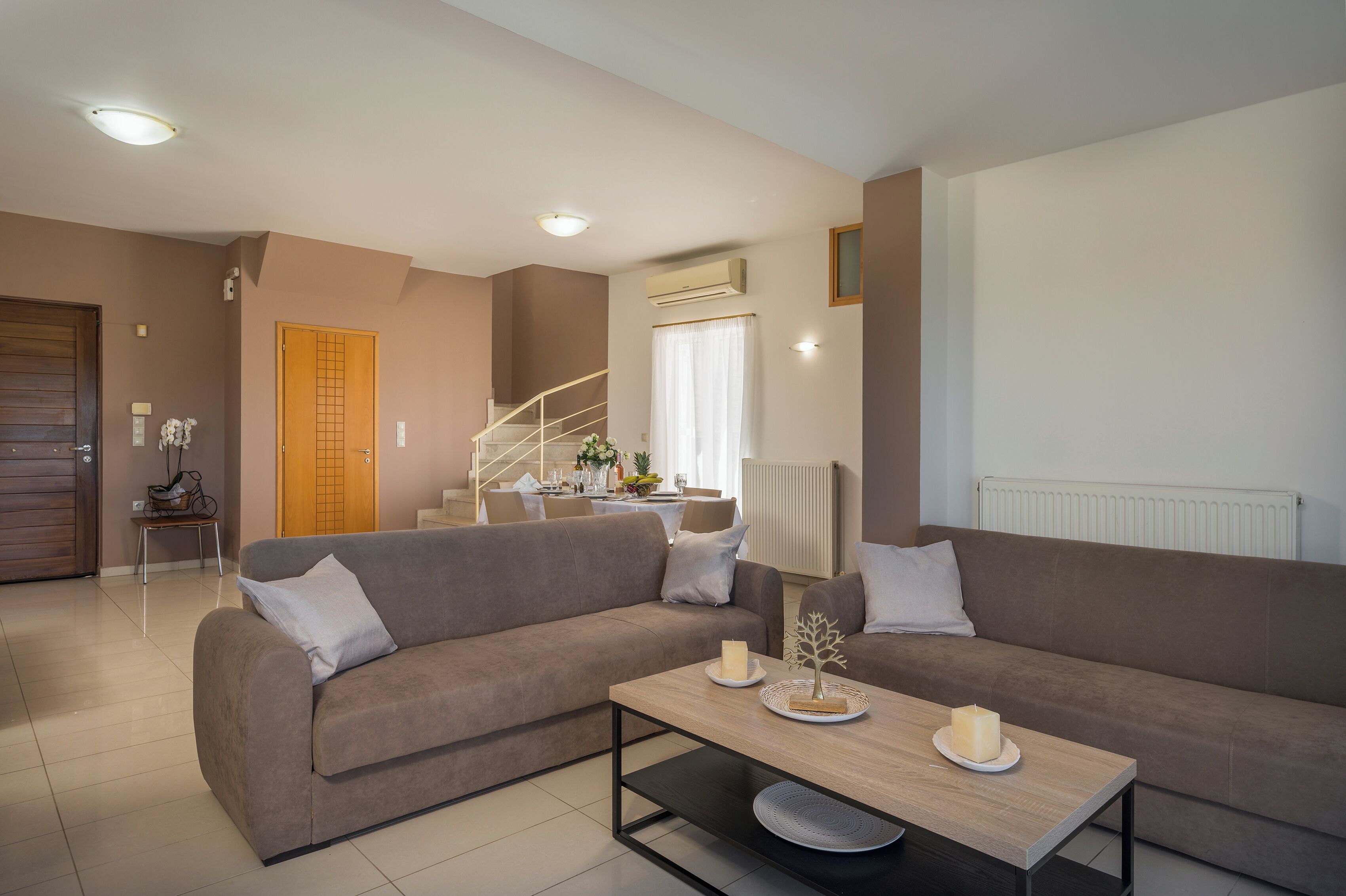 A living room with a sofa, a coffee table, and a staircase leading to a dining area.