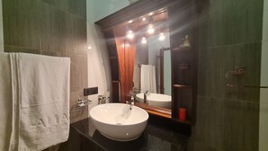 Een badkamer met een groot wit wastafel, een spiegel en een handdoek aan de muur.