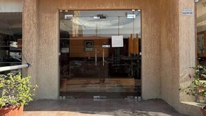 L'ingresso di un edificio con una porta in vetro, una piccola finestra sopra e un pavimento piastrellato.