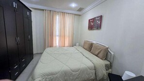 A bedroom with a bed, a wardrobe, a window with curtains, and a painting on the wall. - Basser 6 (Salmiya)