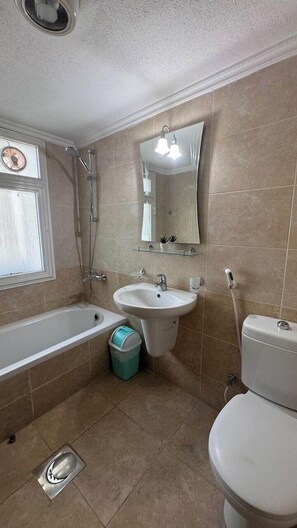 A bathroom with a bathtub, sink, and toilet. - Basser 6 (Salmiya)