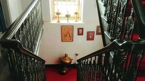 A staircase with ornate black railings and a red carpet. - Urban Trippers Lal Bari Heritage Arindam (Kolkata)
