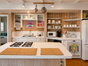 A modern kitchen with a central island, white cabinetry, and a wooden backsplash.
