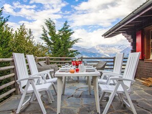 Enjoy meals al fresco in this charming outdoor dining area, surrounded by a mountainous landscape and a cozy cabin.