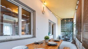 Un'area pranzo con tavolo in legno apparecchiato per quattro persone, ampie finestre e vista sull'esterno.
