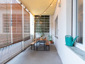 A narrow outdoor patio with a table and benches, string lights, a potted plant, and a watering can. - Lovely apartment for 6 people with WIFI, TV, terrace and pets allowed (Omegna)