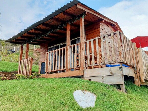 A wooden cabin with a porch, surrounded by a grassy area. - Glamping Isaju (Ginebra)