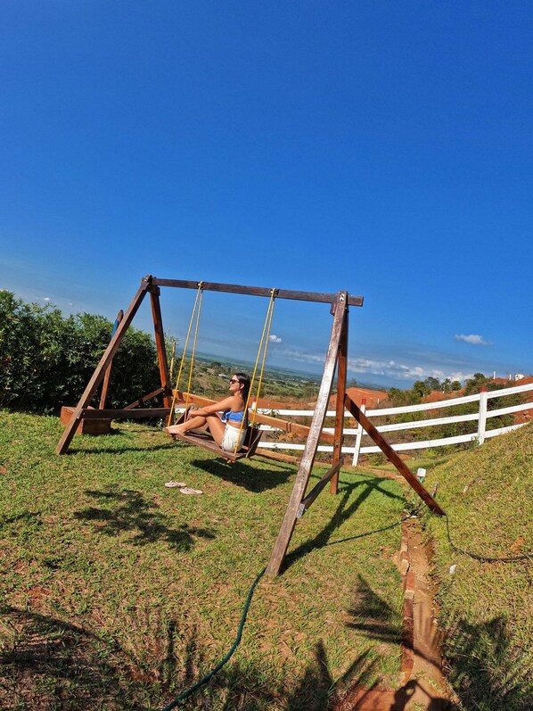 A wooden swing set in a grassy field with a clear blue sky in the background. - Glamping Isaju (Ginebra)