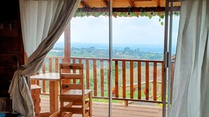 Una sedia di legno su un balcone con vista su un paesaggio verde.