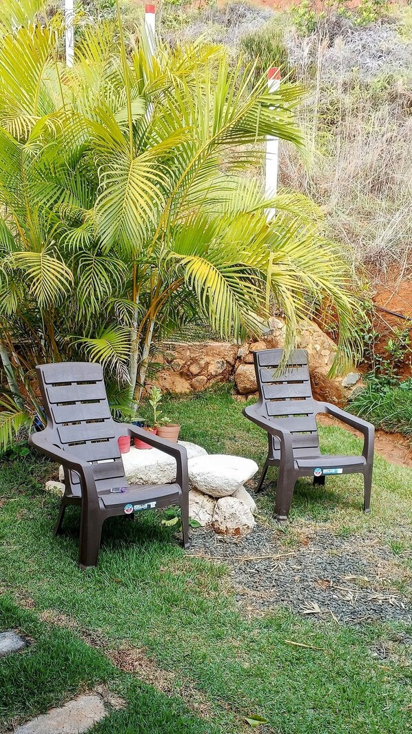 Two outdoor lounge chairs with a small table and potted plants in a garden setting. - Glamping Isaju (Ginebra)