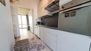 Una cocina moderna con armarios blancos, electrodomésticos de acero inoxidable y un tapete estampado.