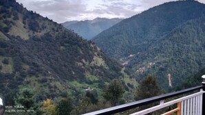 A mountainous landscape with a wooden fence and a small building in the valley.