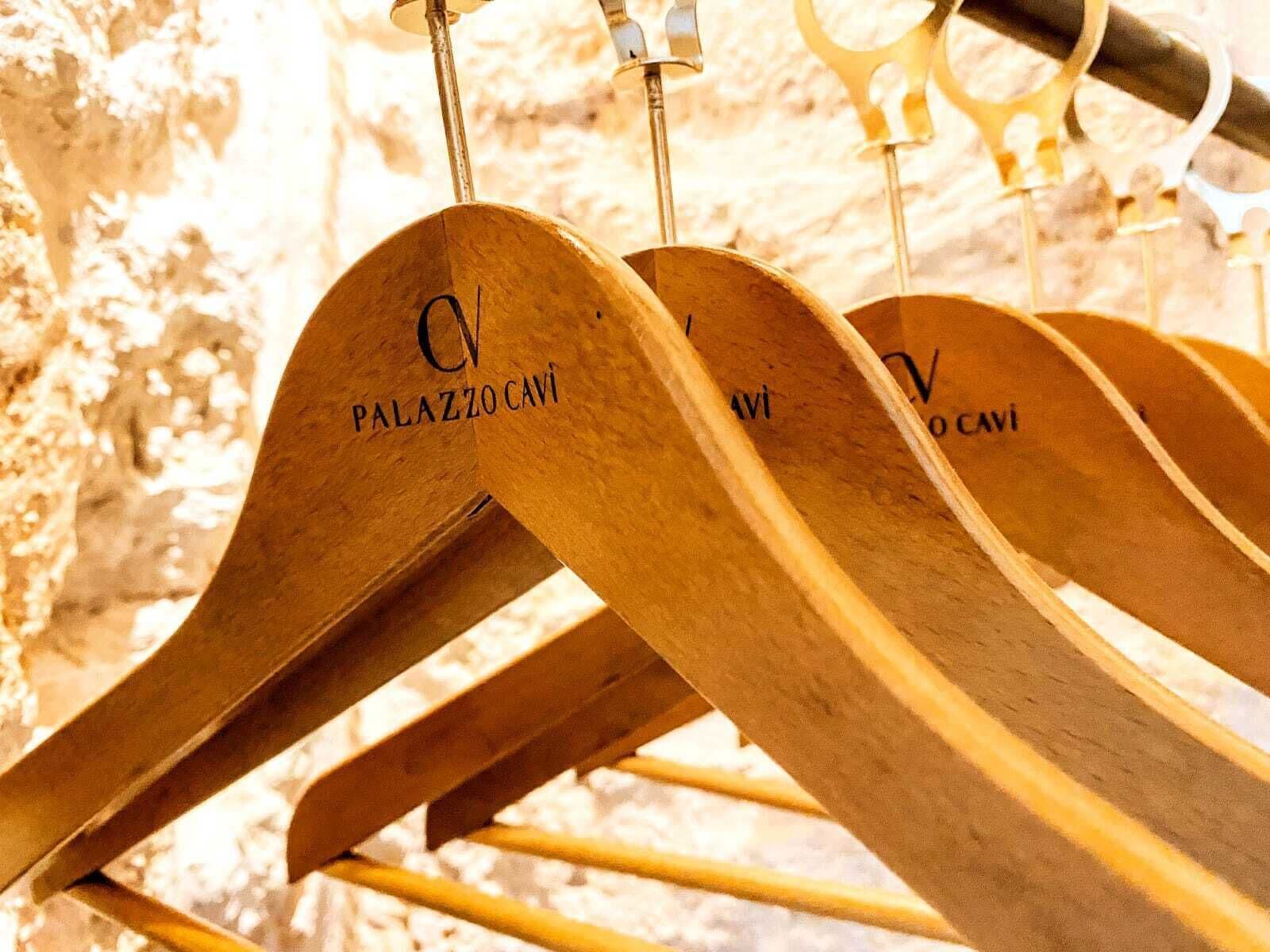Wooden hangers with the text "PALAZZO CAVI" hanging on a rack.