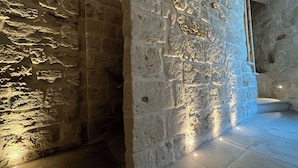 A stone wall with a rough texture and a tiled floor. - Palazzo CAVÌ  (Mola di Bari)