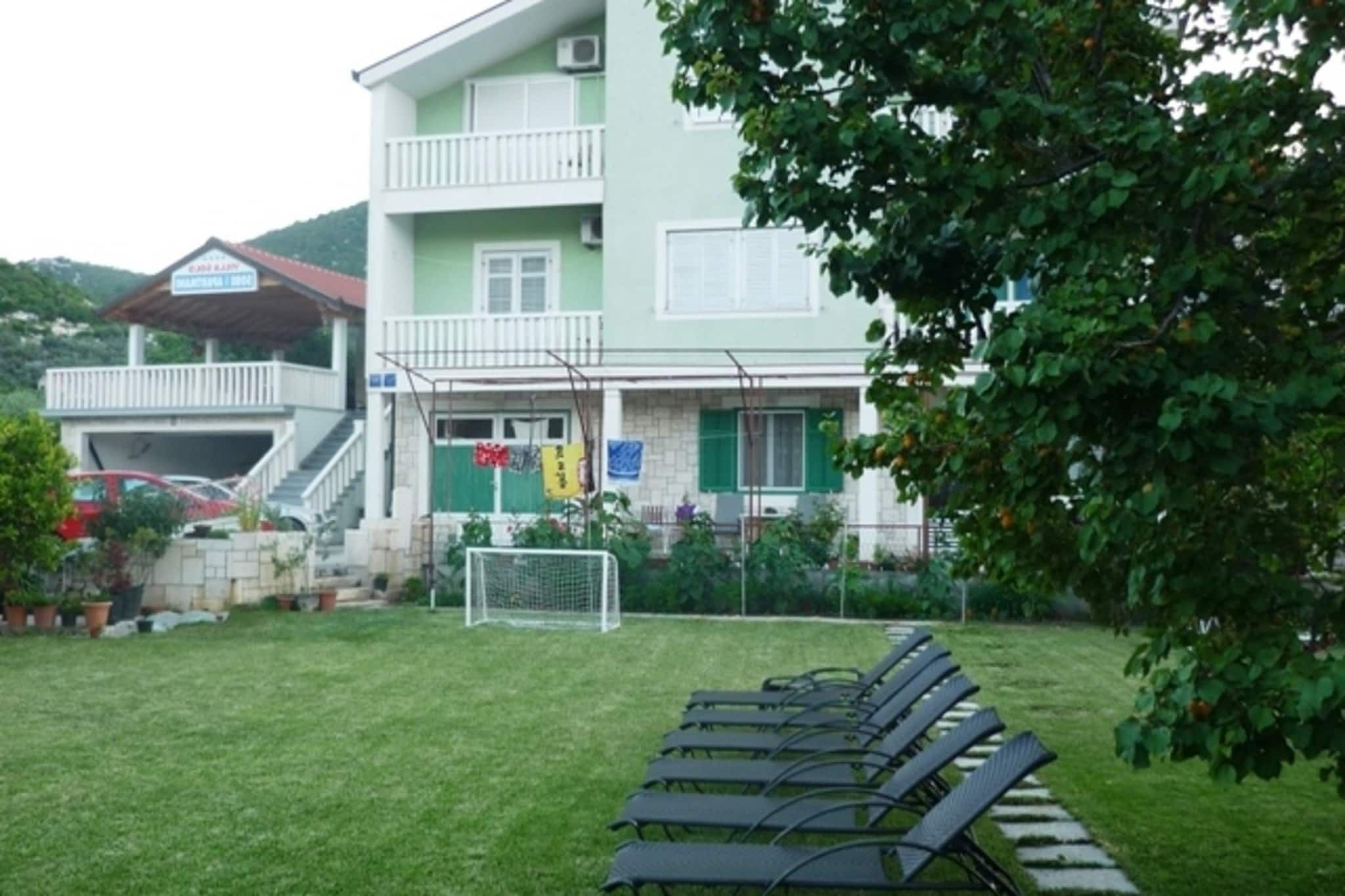 Un bâtiment à deux étages doté d’un balcon, d’une entrée bien visible et d’un petit jardin avec un but de football.