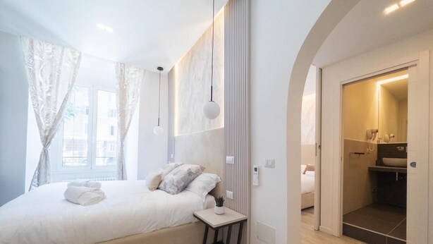 Een moderne slaapkamer met een groot bed, nachtkastjes en uitzicht op de badkamer.