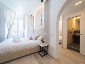 A modern bedroom with a large bed, bedside tables, and a view of the bathroom. - METERS FROM THE VATICAN MUSEUM - IN THE HEART OF ROMA - 6 BEDROOM (Roma)