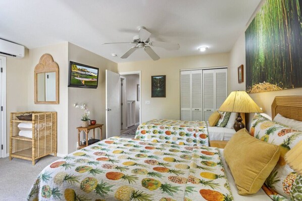A hotel room with two beds, a ceiling fan, a large window with a view, and a wall-mounted TV. - Honu Sunset Steps to the Beach! (Kihei)