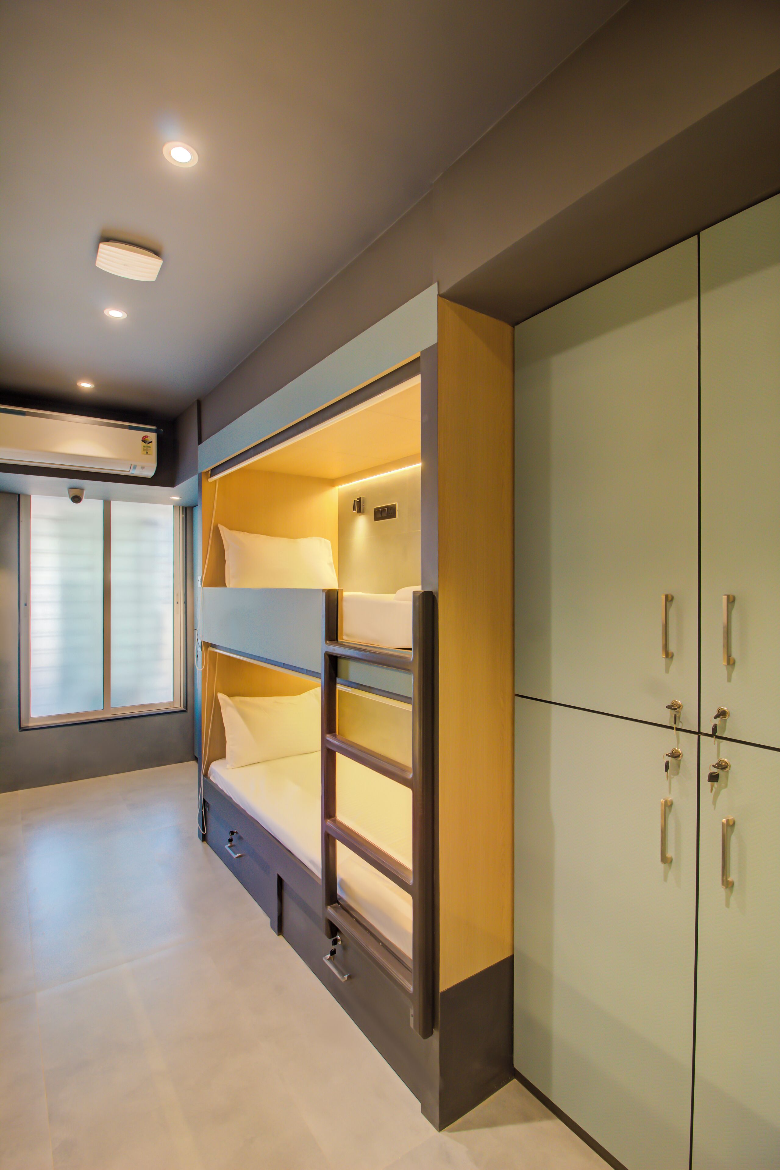 A bunk bed with a ladder, a wardrobe with multiple doors, and a window with blinds.