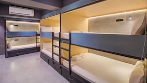 Hotellihuone, jossa on kerrossängyt, yöpöytä, lamppu ja ilmastointilaite.