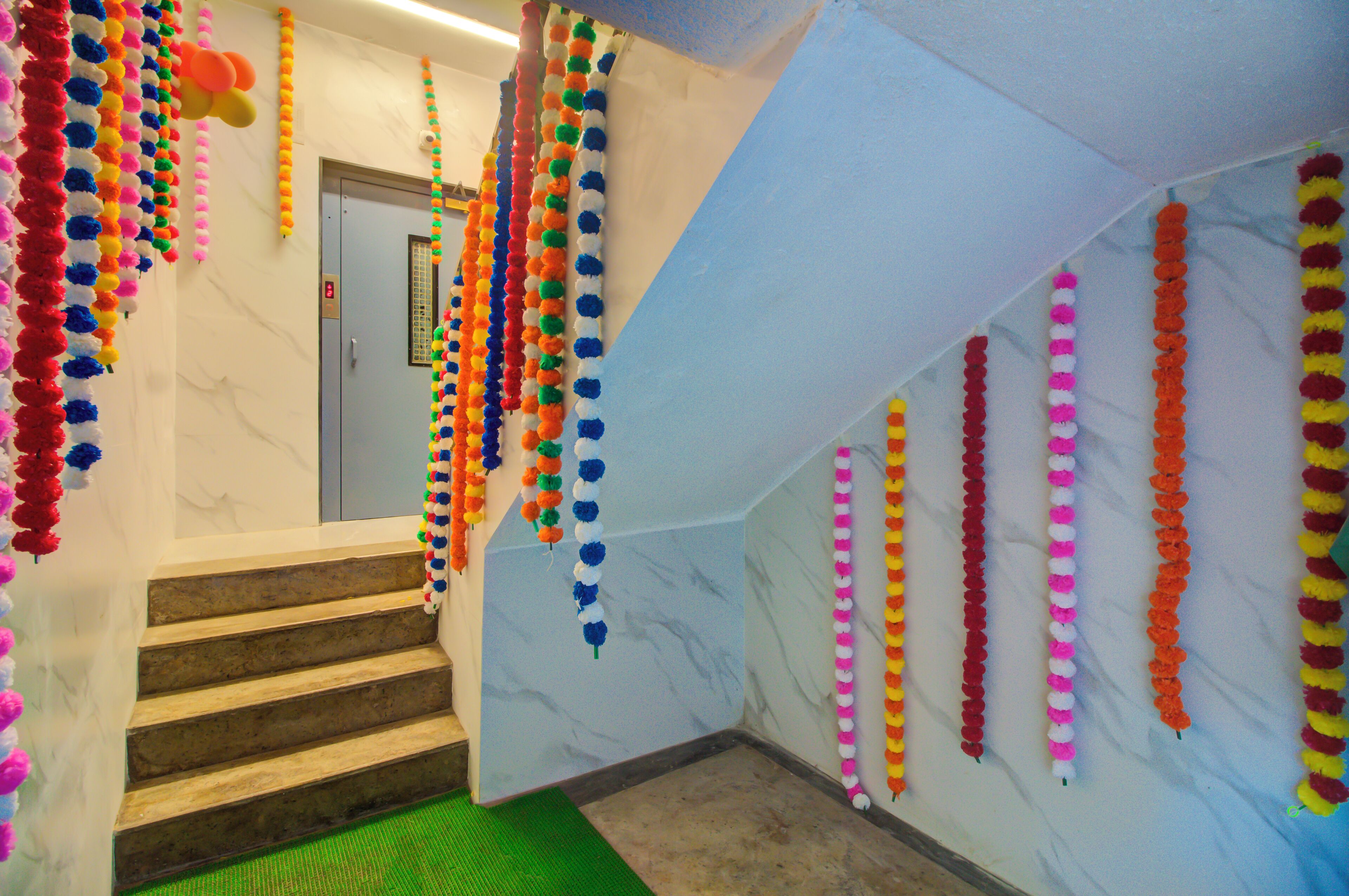 A staircase with colorful pom-pom garlands hanging from the ceiling and walls.