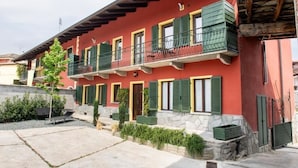 Un bâtiment rouge avec des volets verts et un balcon.