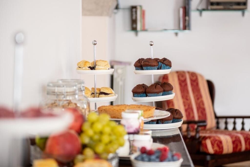 A three-tiered dessert stand with various pastries and a fruit bowl in the foreground.