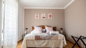 Une chambre à coucher comprenant un lit, deux tables de chevet, un fauteuil suspendu et trois œuvres d’art murales.