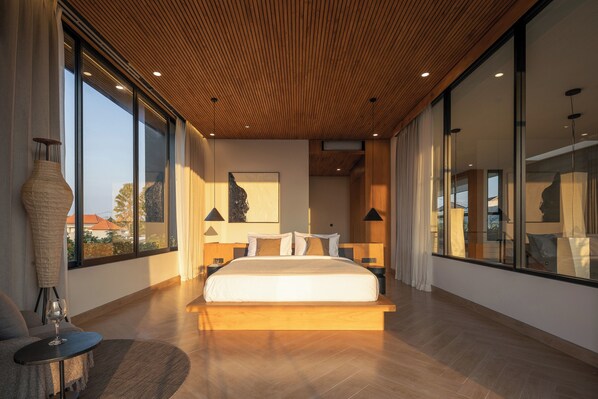 Un dormitorio moderno con una cama grande, techo de madera, ventanas amplias y vistas al exterior.