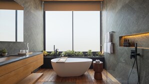 Un baño moderno con una bañera independiente, tocador de madera y un ventanal que proporciona luz natural.