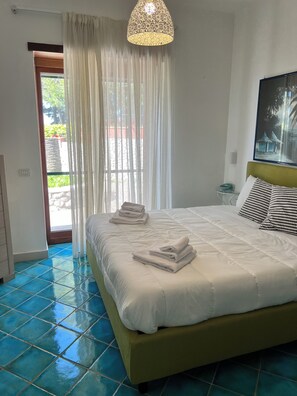 A bedroom with a bed, a hanging light fixture, a window with curtains, and a view of greenery outside. -  La Canostra Capri - luxury ROOM ad Anacapri (Anacapri)