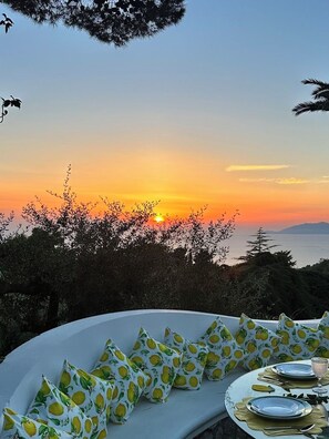 A sunset view from a dining area with a table set for two, surrounded by foliage. -  La Canostra Capri - luxury ROOM ad Anacapri (Anacapri)
