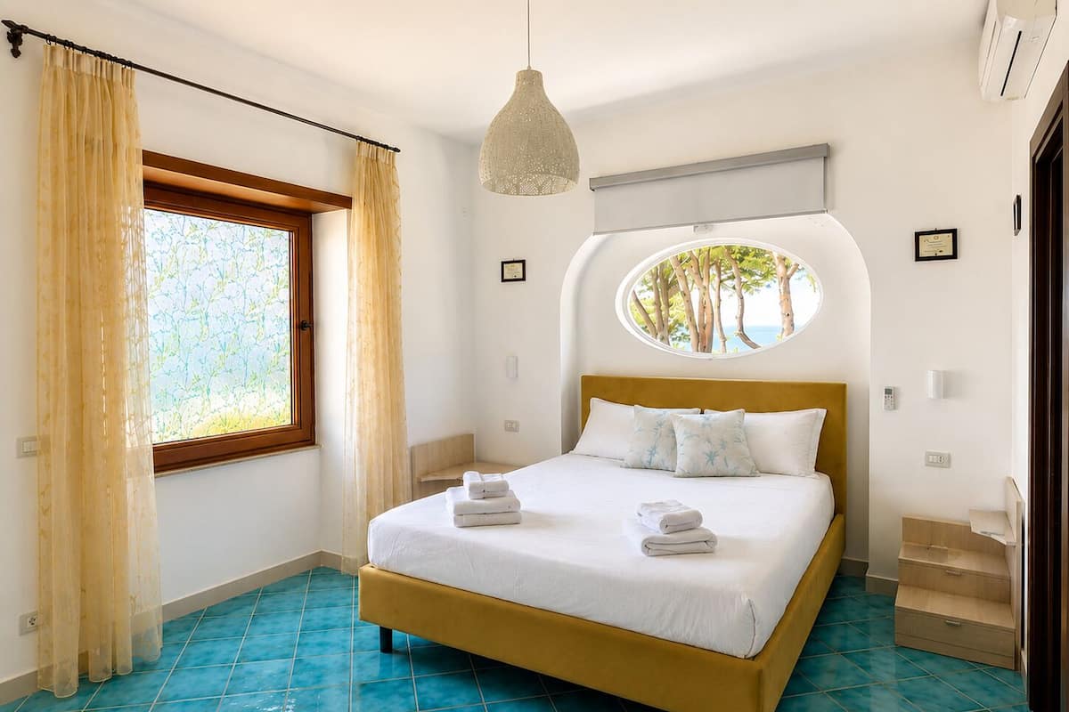 Una camera da letto con un letto, tende, una finestra, un lampadario e una piccola scala.