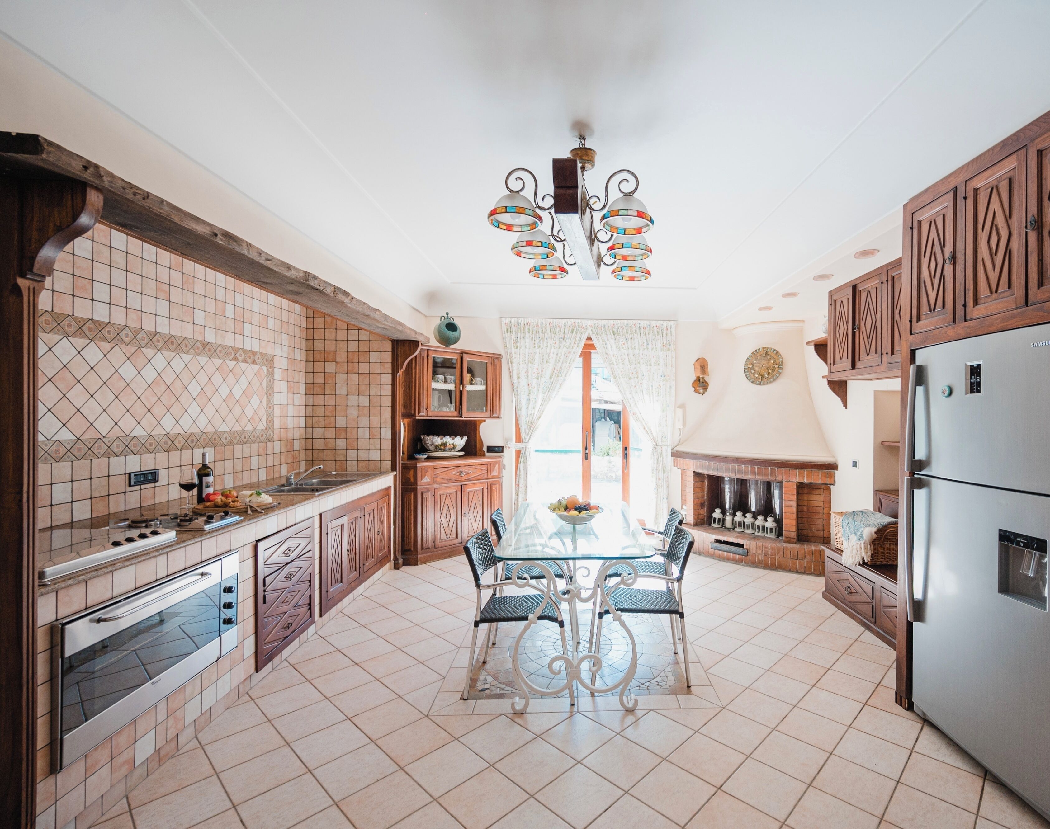 A kitchen with a dining table, cabinets, a refrigerator, and a fireplace.
