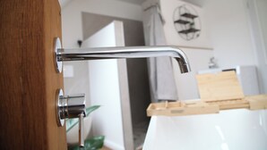 A modern bathroom with a chrome faucet, wooden door, and a white sink. - Fewo zum Königreich.... where others go on vacation  (Westerwalsede)
