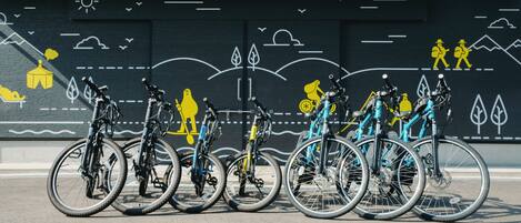 A row of bicycles parked in front of a mural with various outdoor scenes.