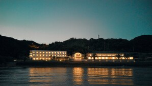 A waterfront hotel with multiple buildings, a dock, and a hill in the background. - Colorit GOTO ISLANDS (Goto)