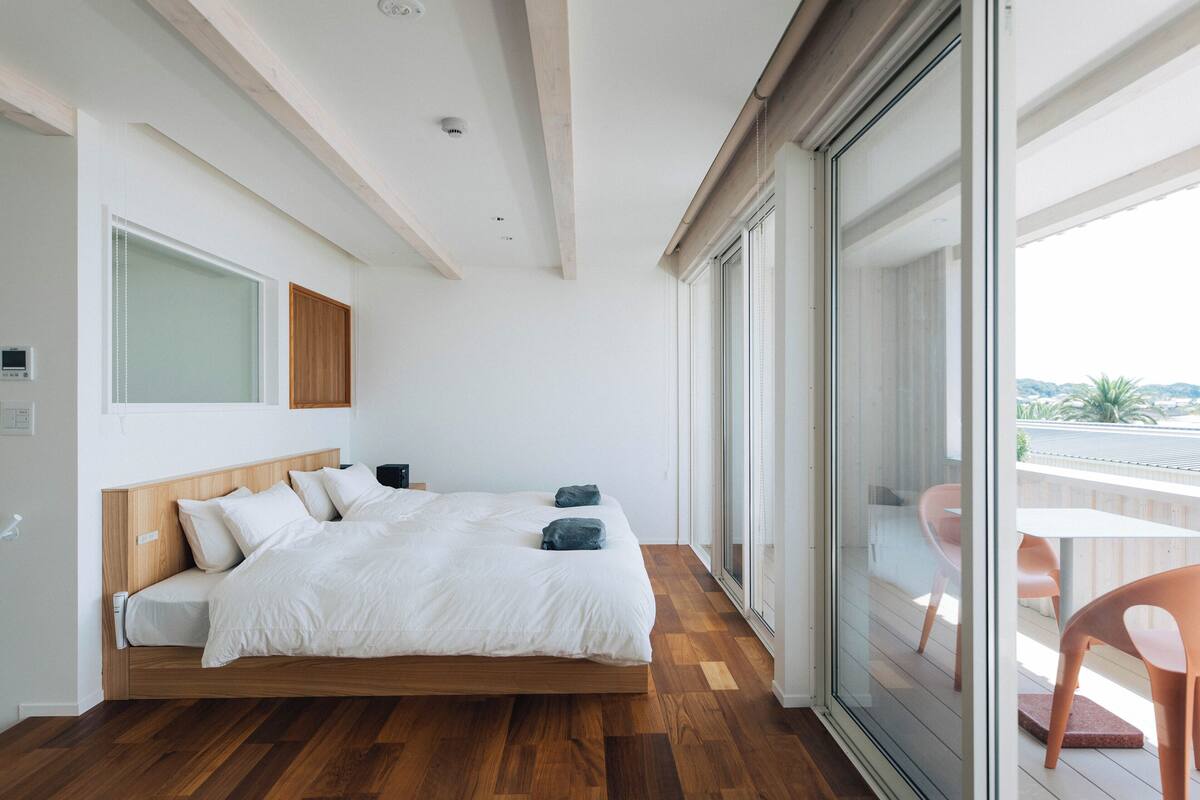 Un dormitorio moderno con una cama de madera, ventanas amplias y vistas al exterior.
