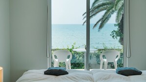 A bedroom with a bed, two pillows, and a view of the sea through a large window. - Colorit GOTO ISLANDS (Goto)