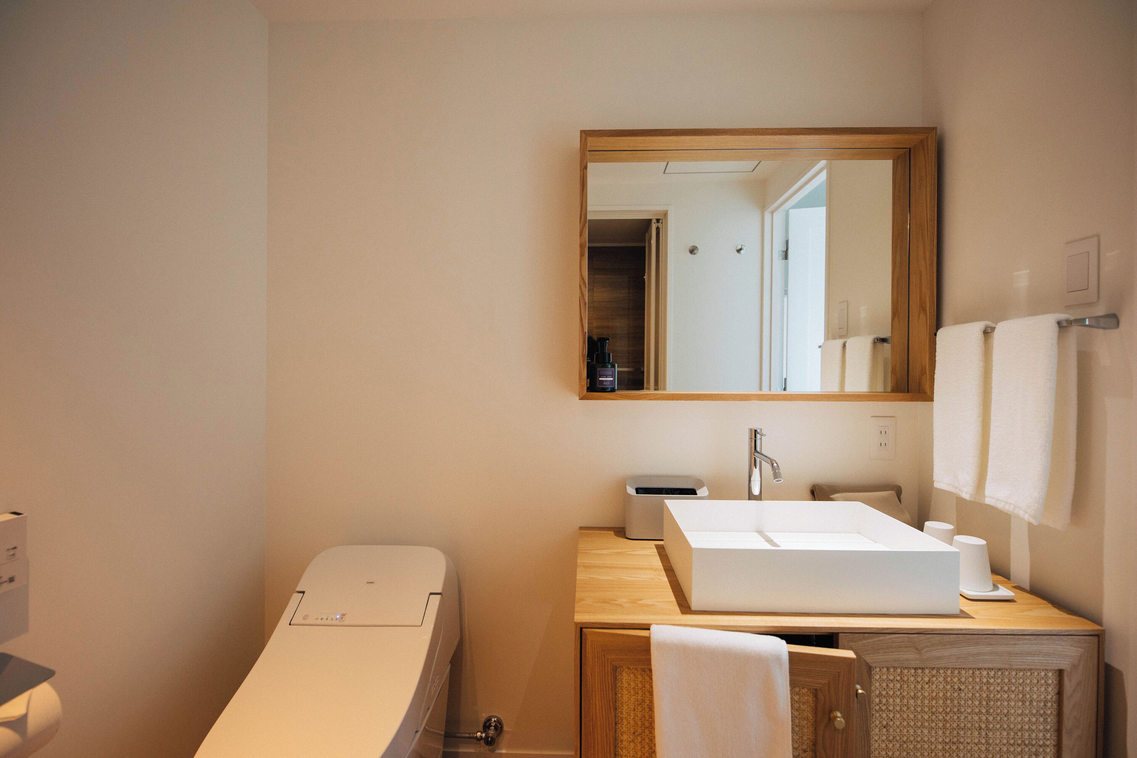 Une salle de bain avec un lavabo blanc, un miroir et un meuble en bois.